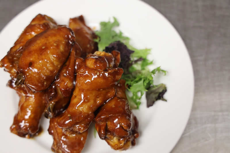 a plate of chicken wings on a bed of greens