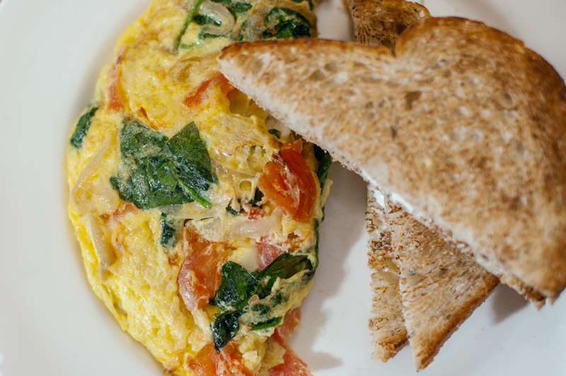 omelet with tomatoes, spinach, onions and cheese with side of toast